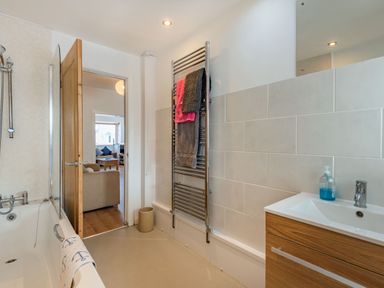 A bathroom with a bathtub towel rail sink and a door opening to a living room at 2 Tregof Terrace in Cemaes Bay