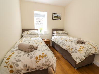 A bedroom with two single beds bedside table and table lamp at Y Felin - Moana Borth near Aberystwyth