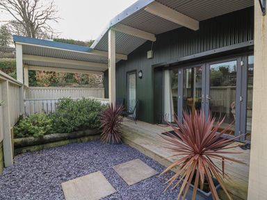 A covered patio area with wooden decking plants and a gravel ground at Y Felin - Moana in Borth near Aberystwyth