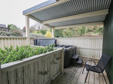 A covered wooden deck with a hot tub and a black chair at Y Felin - Moana in Borth near Aberystwyth