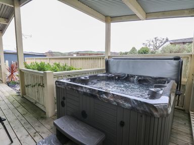 An outdoor covered wooden deck with a hot tub and plants at Y Felin - Moana in Borth near Aberystwyth