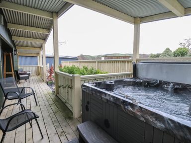 A covered wooden deck with a hot tub chairs and table at Y Felin - Moana in Borth near Aberystwyth