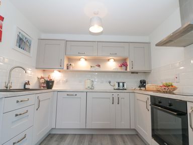 A kitchen with grey cabinets a sink toaster kettle and oven at White Rose Apartment in Filey