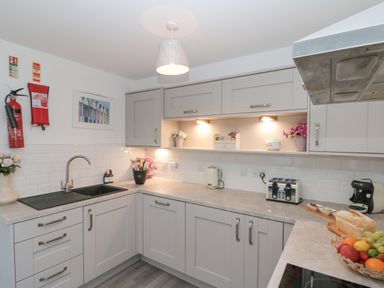 A kitchen with grey cabinets a black sink a kettle toaster and coffee machine at White Rose Apartment in Filey