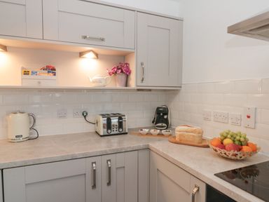 A kitchen corner with a kettle toaster coffee machine bread and fruit bowl at White Rose Apartment in Filey