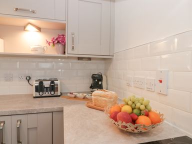 A kitchen countertop with a toaster coffee machine bread and a fruit bowl at White Rose Apartment in Filey