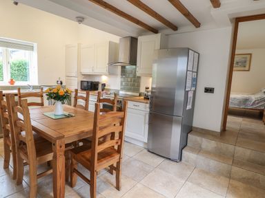 A kitchen with wooden dining table and chairs a refrigerator and white cabinets at Kingfisher in Whitby