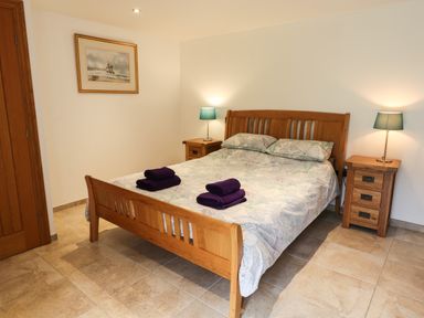 A bedroom with a wooden double bed two bedside tables with lamps and folded towels on the bed at Kingfisher Whitby