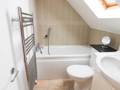 A bathroom with a bathtub toilet sink and a towel radiator at Kingfisher in Whitby