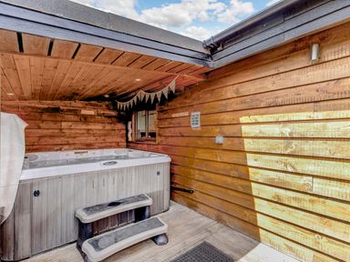 A wooden outdoor hot tub with steps under a wooden roof at Kingfisher Lodge in Brandesburton