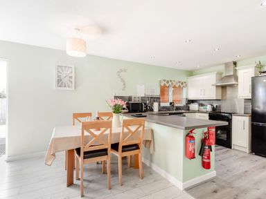 A kitchen and dining area with a table and chairs a countertop and appliances at Kingfisher Lodge in Brandesburton