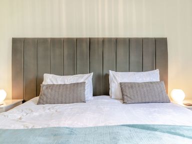 A bed with a grey upholstered headboard two white pillows and two grey cushions at Kingfisher Lodge in Brandesburton