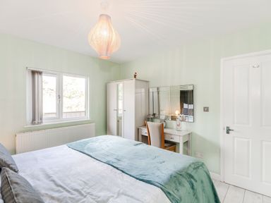 A bedroom with a bed covered in white and teal bedding a white wardrobe a desk with a chair and a mirror on the wall at Kingfisher Lodge in Brandesburton