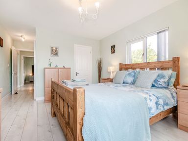 A bedroom with a wooden bed and blue bedding a chest of drawers and a window at Kingfisher Lodge in Brandesburton