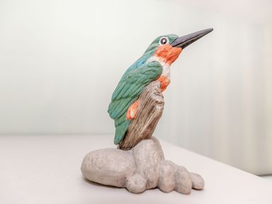 A figurine of a bird on a rock on a white surface