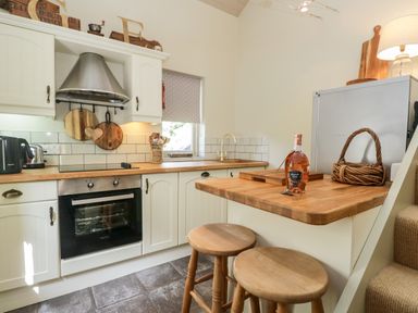 A kitchen with wooden countertops stools a oven and a window at Gable End in Coniston near Hawkshead