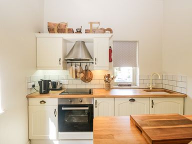 A kitchen with a stove oven wooden countertop cutting boards and a window with a blind at Gable End Coniston near Hawkshead
