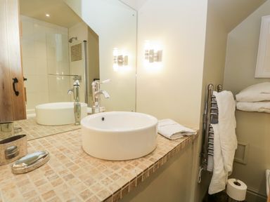 A bathroom sink with a round basin on a tiled counter and towels on a rail at Gable End Coniston near Hawkshead