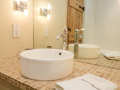 A bathroom countertop with a white round sink and two modern faucets at Gable End Coniston near Hawkshead