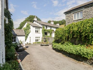 A courtyard with white and stone houses covered in ivy and greenery at Gable End in Coniston near Hawkshead