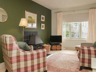 A living room with an armchair, fireplace, and television at Gable End in Coniston near Hawkshead