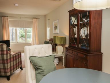 A living room with a chair, table and bookcase at Gable End in Coniston near Hawkshead
