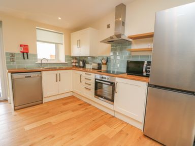 A kitchen with white cabinets wooden countertops a stainless steel oven refrigerator and dishwasher at Y Felin - Celyn in Borth