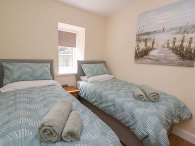 A bedroom with two single beds with blue patterned bedding and rolled towels on the beds at Y Felin - Celyn in Borth