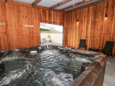An indoor wooden room with a hot tub and two black chairs at Y Felin - Celyn in Borth