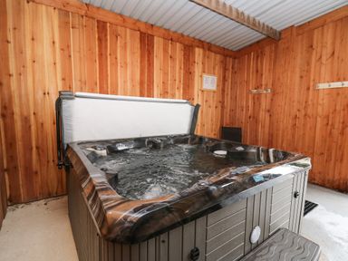 An indoor hot tub with water in a wooden room with hooks on the walls at Y Felin - Celyn in Borth
