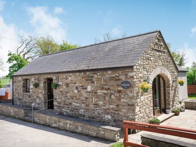 A stone cottage with a slate roof and hanging flower pots at Highbury in Spittal near Haverfordwest