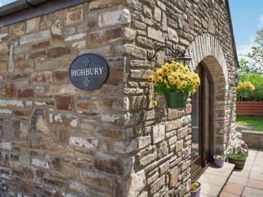 Stone exterior wall with a sign reading Highbury and hanging flower pots at Highbury in Spittal near Haverfordwest