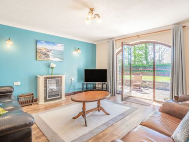 A living room with a wooden coffee table two leather sofas a TV and a fireplace at Highbury in Spittal near Haverfordwest