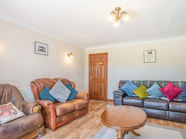 A living room with two brown leather sofas a round wooden coffee table and a wooden door at Highbury in Spittal near Haverfordwest