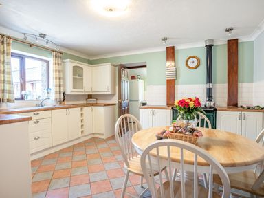 A kitchen with a wooden table and chairs a stove and cabinets at Highbury in Spittal near Haverfordwest