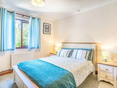 A bedroom with a bed with blue and white bedding and two bedside tables with lamps at Highbury in Spittal near Haverfordwest