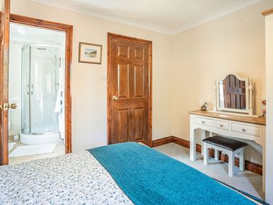 A bedroom with a dressing table and a bathroom with a shower visible through an open door at Highbury in Spittal near Haverfordwest