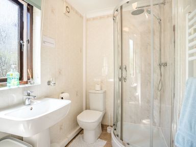 A bathroom with a sink, toilet, shower enclosure, and window at Highbury in Spittal near Haverfordwest
