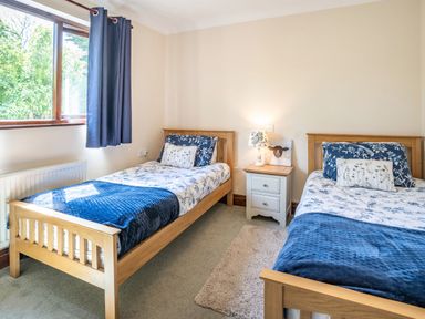 A bedroom with two single wooden beds with blue and white bedding and a small bedside table with a lamp at Highbury in Spittal near Haverfordwest