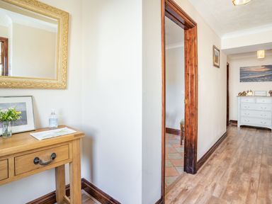 A hallway with a wooden table and mirror and a white dresser in the background at Highbury in Spittal near Haverfordwest