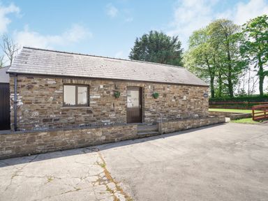 A stone building with a shingled roof and a door and window at Highbury in Spittal near Haverfordwest