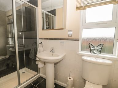 A bathroom with a shower enclosure sink toilet and mirror cabinet at Little Gem Lodge in Charlesfield near St Boswells