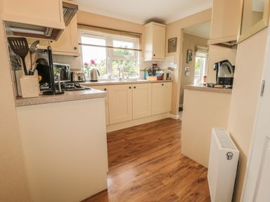 A kitchen with cream cabinets wooden floor and countertop appliances at Little Gem Lodge Charlesfield near St Boswells