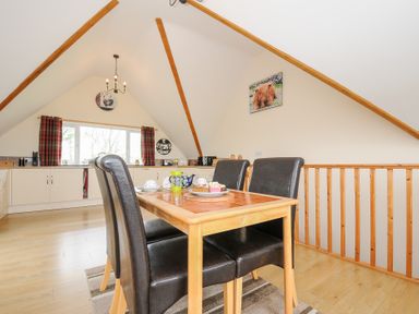 A kitchen dining area with a wooden table and four black chairs under a pitched ceiling at Treview in Launceston
