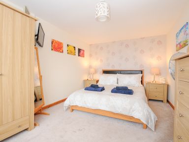 A bedroom with a double bed flanked by two bedside tables with lamps wooden wardrobe and chest of drawers at Treview Launceston