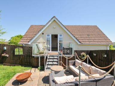 An outdoor patio area with wicker furniture a fire pit and a small balcony attached to a house at Treview in Launceston