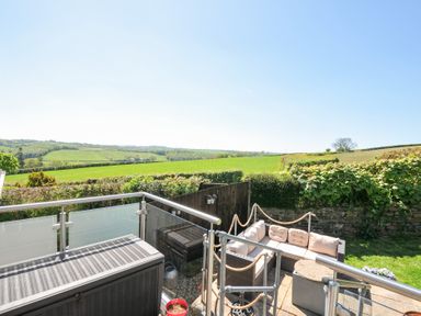 A patio with outdoor seating and table overlooking fields and hedges at Treview Launceston