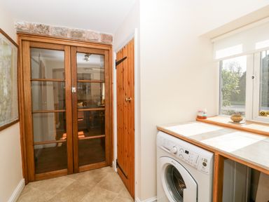 A utility room with a washing machine under a countertop and large glass wooden doors at The Pound in Trellech near Monmouth