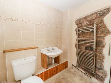 A bathroom with a toilet a sink and a towel rail on a stone wall at The Pound in Trellech near Monmouth