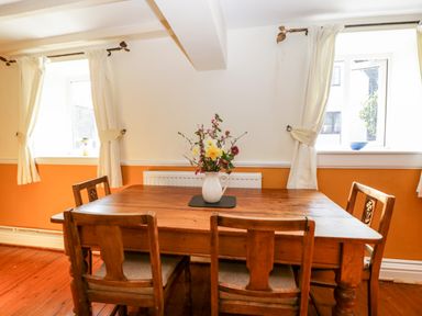 A dining room with a wooden table and four chairs with flowers in a white vase on the table at The Pound in Trellech near Monmouth